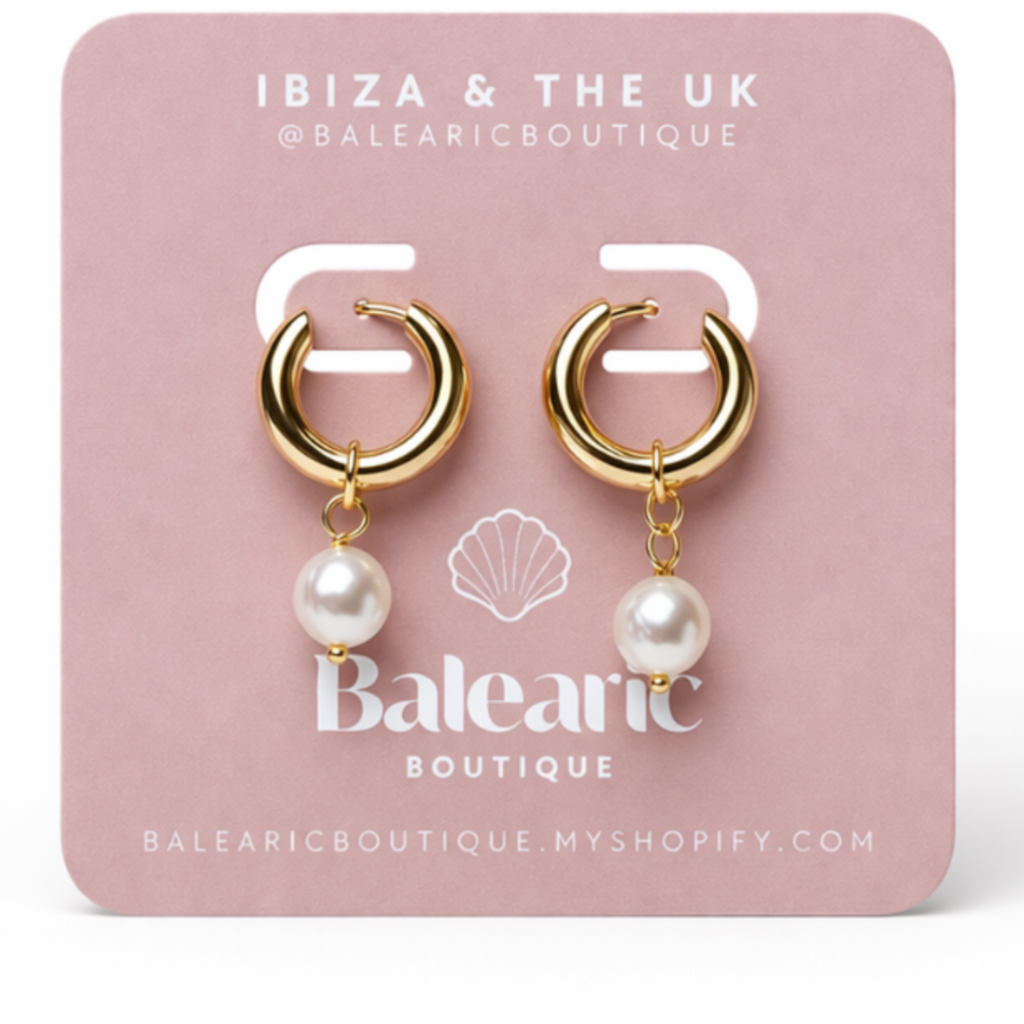 Gold hoop earrings with pearls on a pink card from Balnearic Boutique.