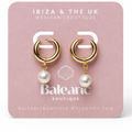 Gold hoop earrings with pearls on a pink card from Balnearic Boutique.