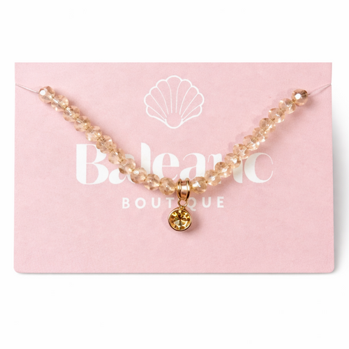 bracelet with a gold charm on a pink card with 'Belenic Boutique' branding.