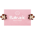 Pair of flower-shaped earrings with pearl centers on a pink card with 'Balearon Boutique' logo.