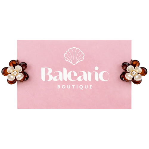 Pair of flower-shaped earrings with pearl centers on a pink card with 'Balearon Boutique' logo.