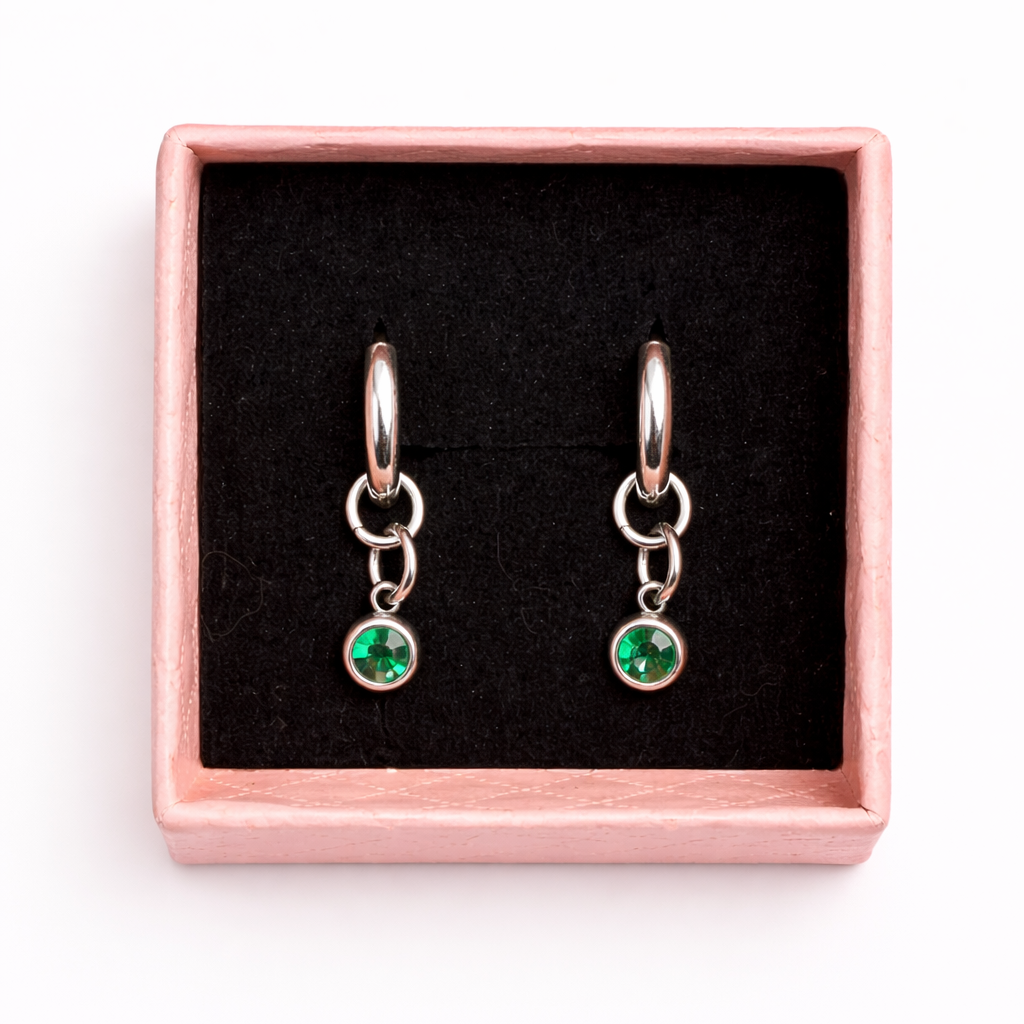 Pair of earrings with green gemstones in a rose gold box on a white background