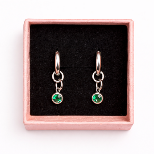 Pair of earrings with green gemstones in a rose gold box on a white background