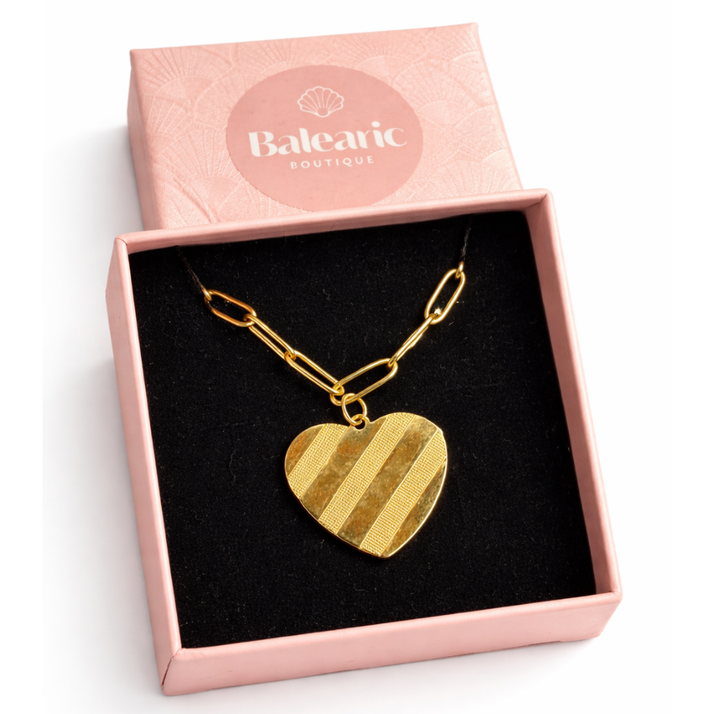 Gold heart-shaped necklace in a pink box with 'Balearic Boutique' branding.