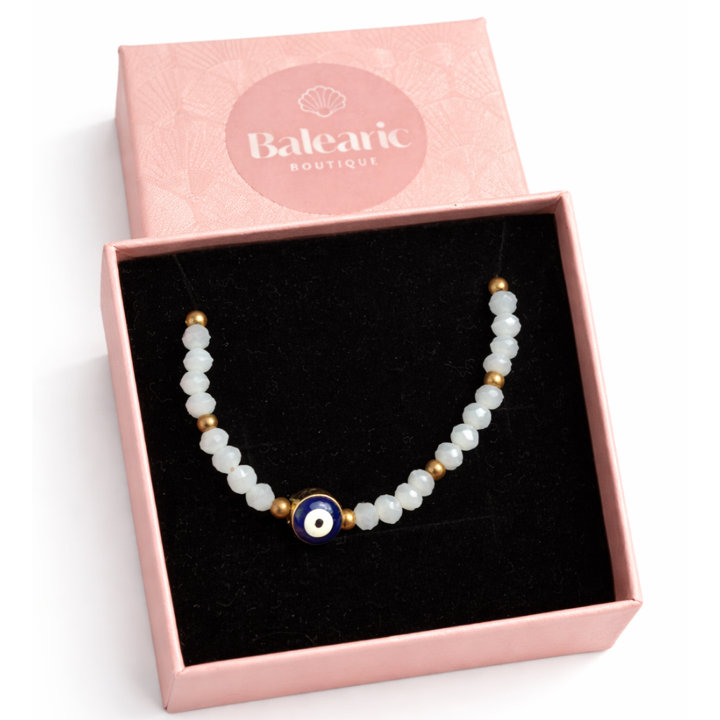 necklace with a blue evil eye bead in a pink 'Balearic Boutique' box on a white background