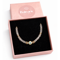 Pearl bracelet with gold and blue accents in a pink 'Balearic Boutique' box on a white background