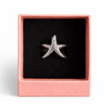 Star-shaped silver ring in a pink box on a white background