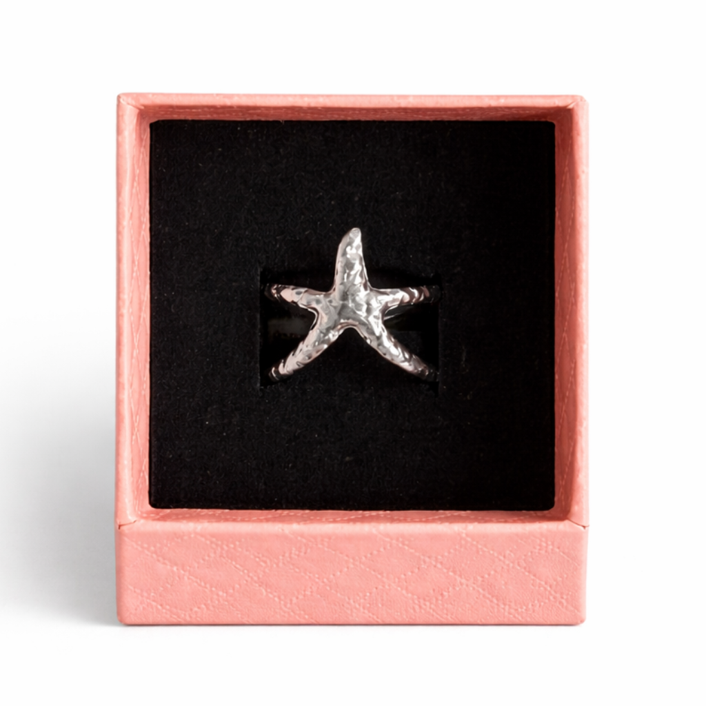 Star-shaped silver ring in a pink box on a white background