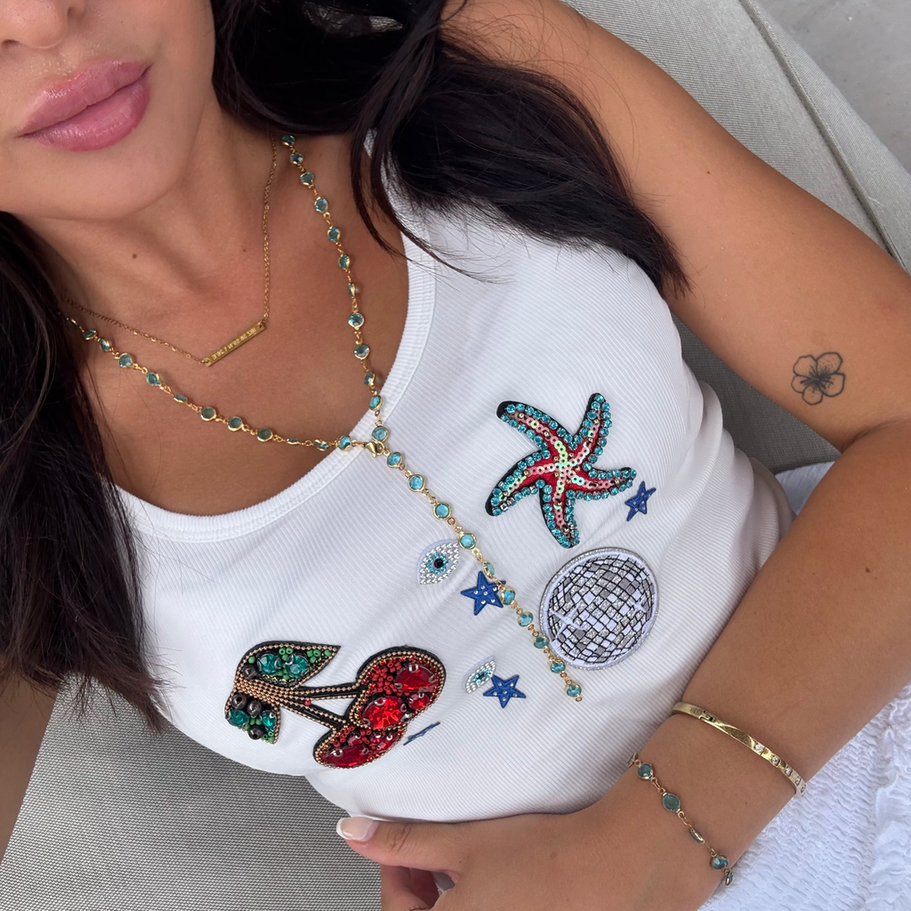 Woman wearing a white top with colorful embellishments and accessories.