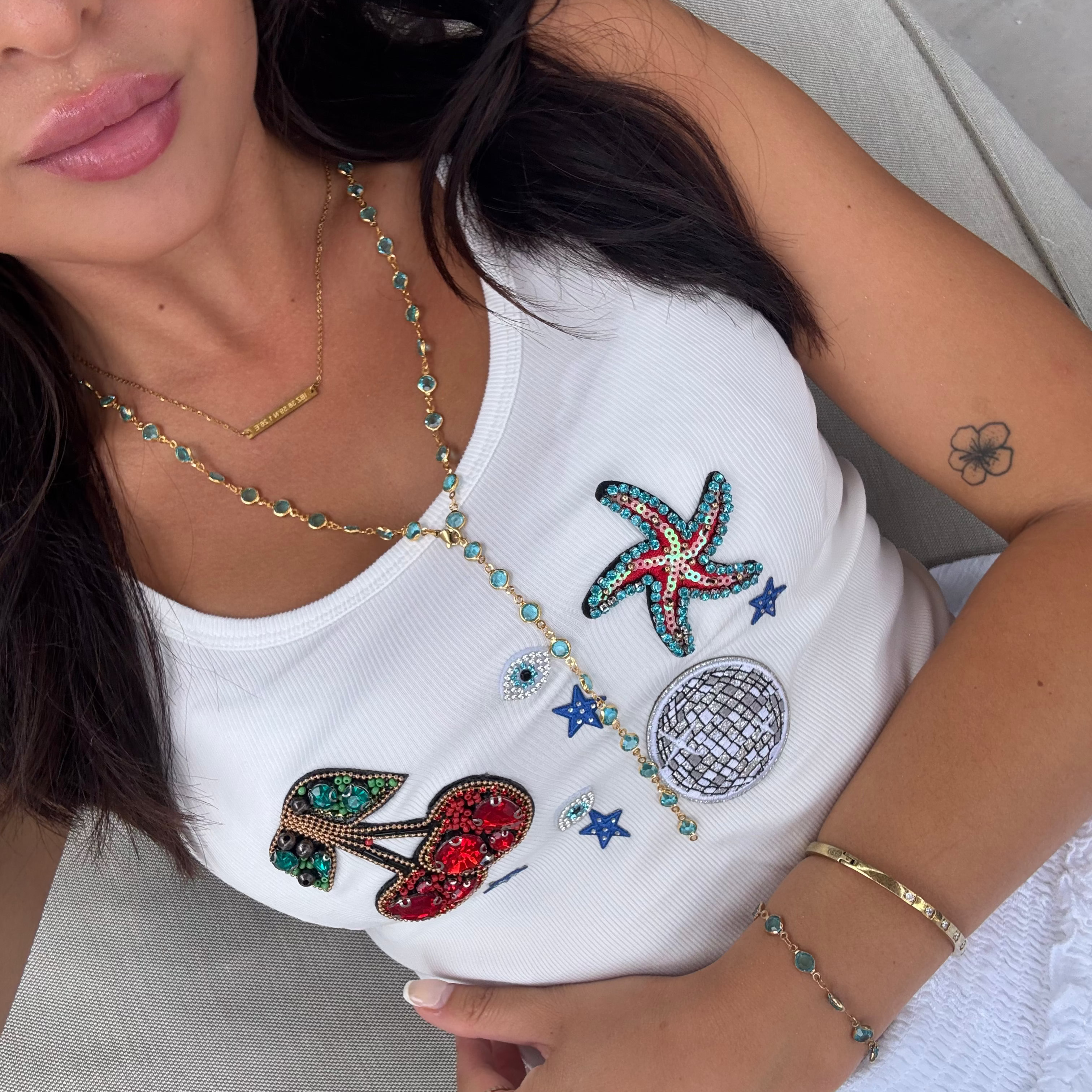 Woman wearing a white top with colorful embellishments and accessories.