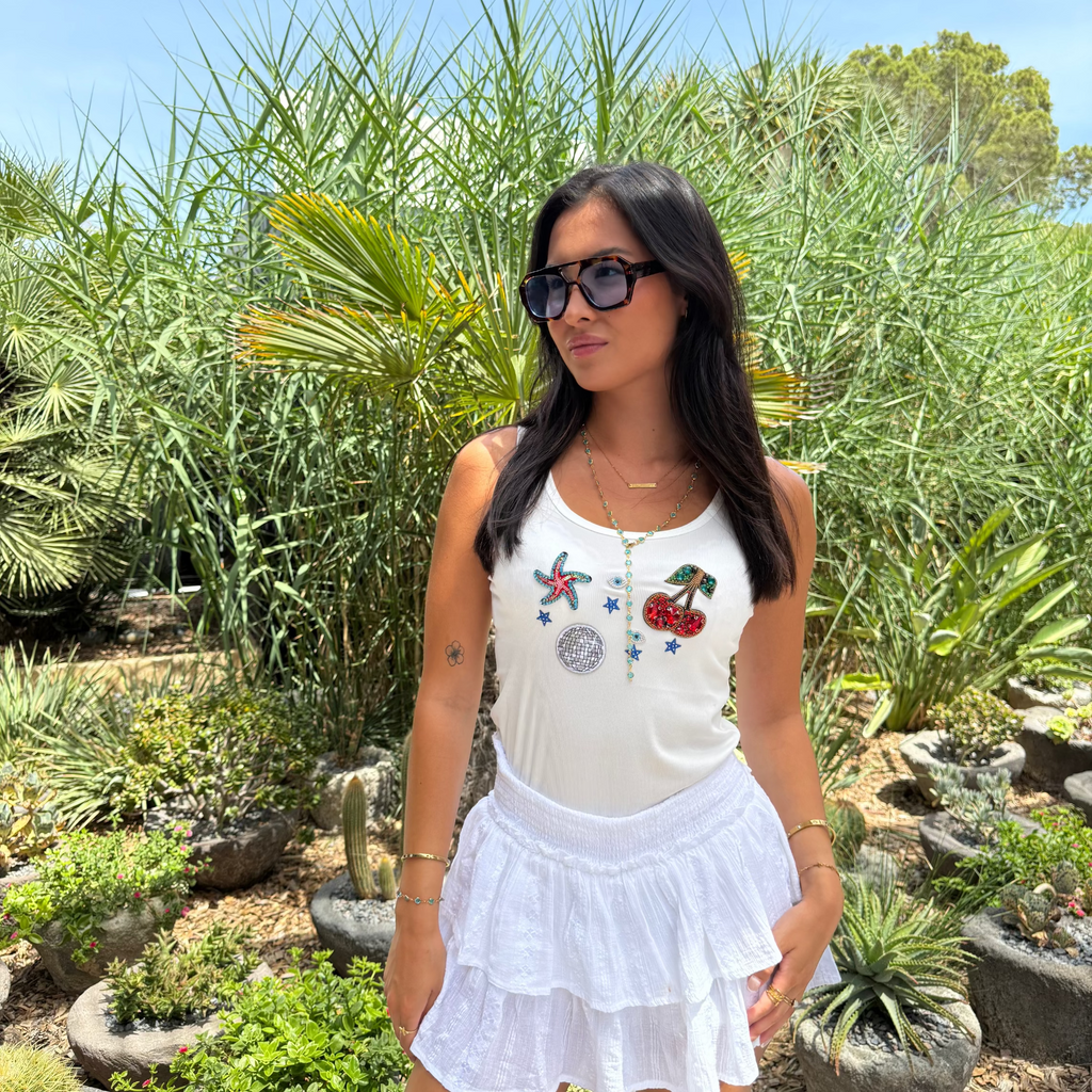 Woman in a white outfit with decorative elements standing in a garden setting