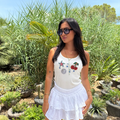 Woman in a white outfit with decorative elements standing in a garden setting