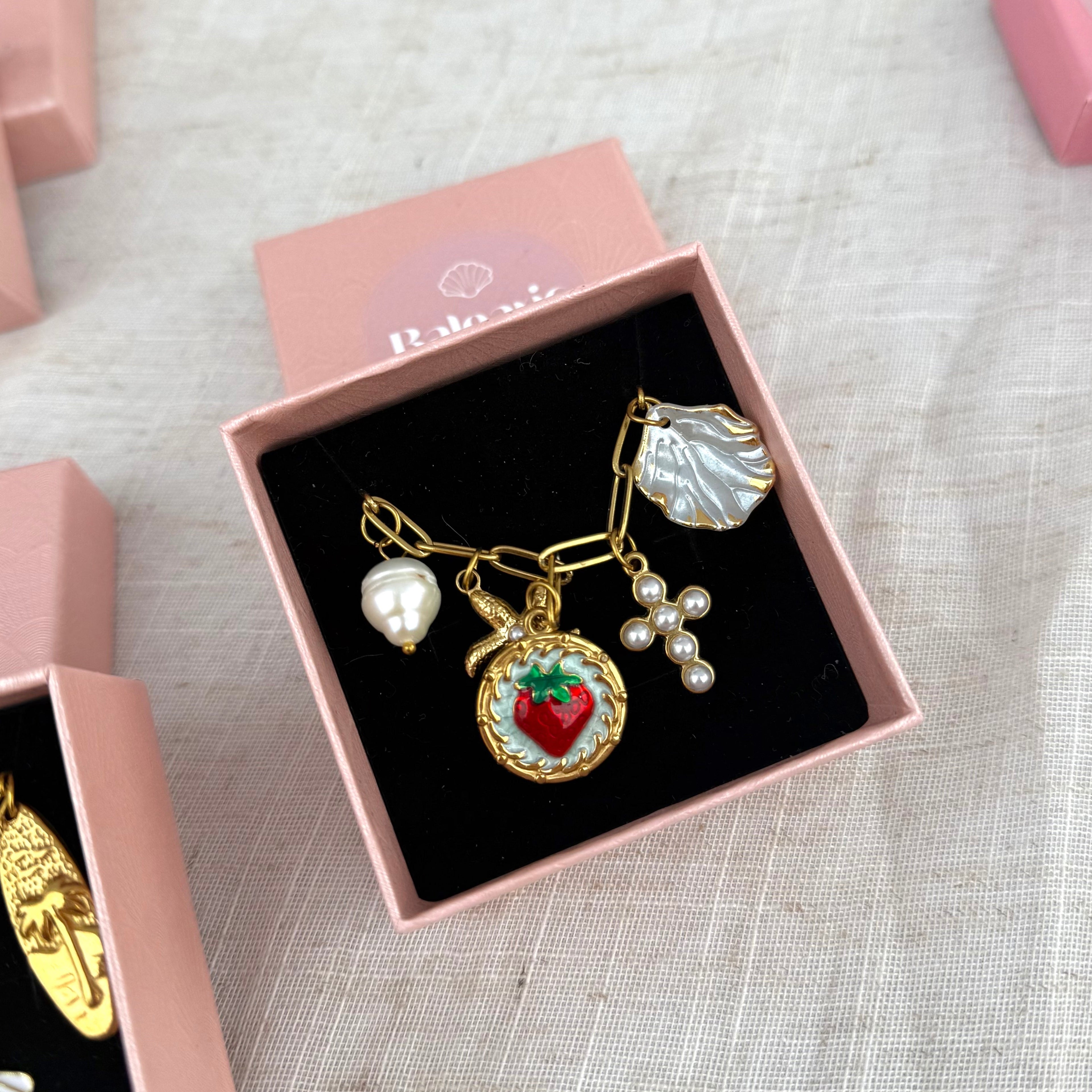 Necklace with charms in a pink box on a textured surface