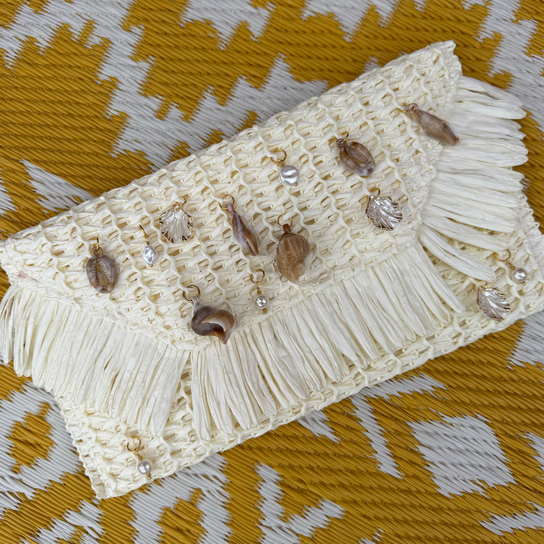 Beige clutch bag with decorative elements on a patterned fabric background