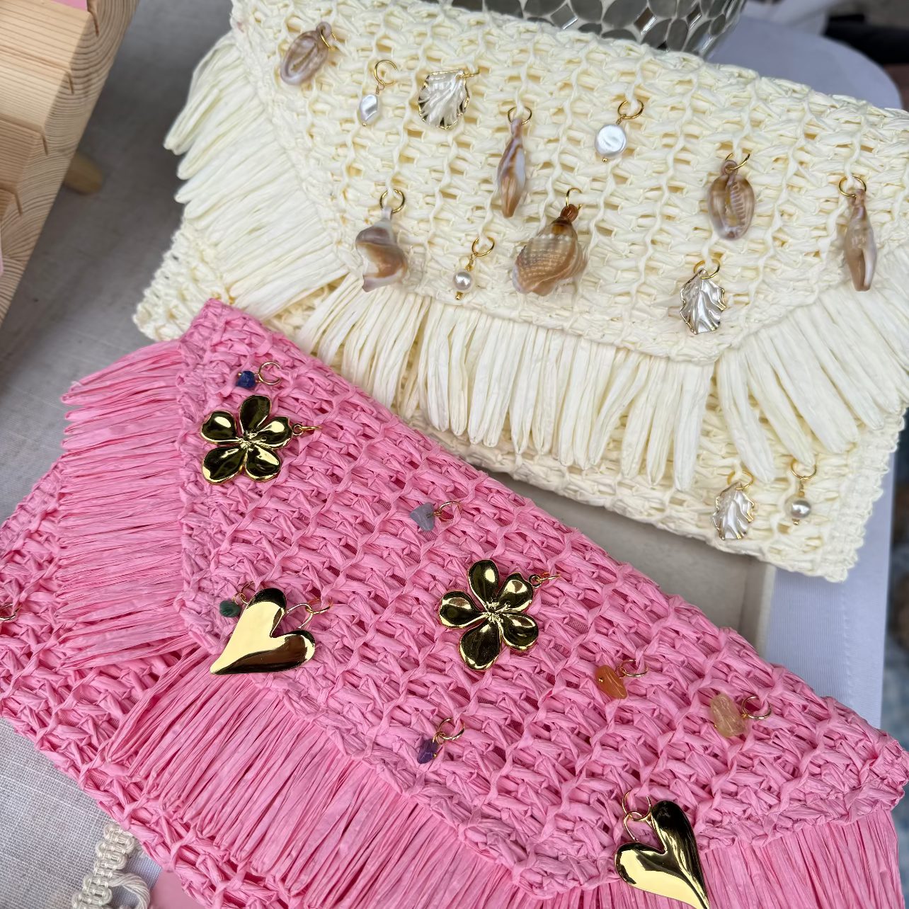 Two crocheted bags, one pink and one beige, with decorative pins on a surface.