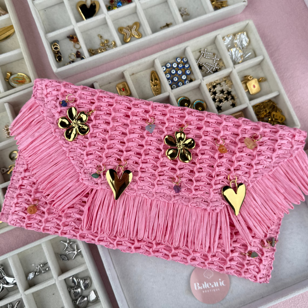 Pink clutch with gold embellishments on a pink jewelry box with jewelry compartments.
