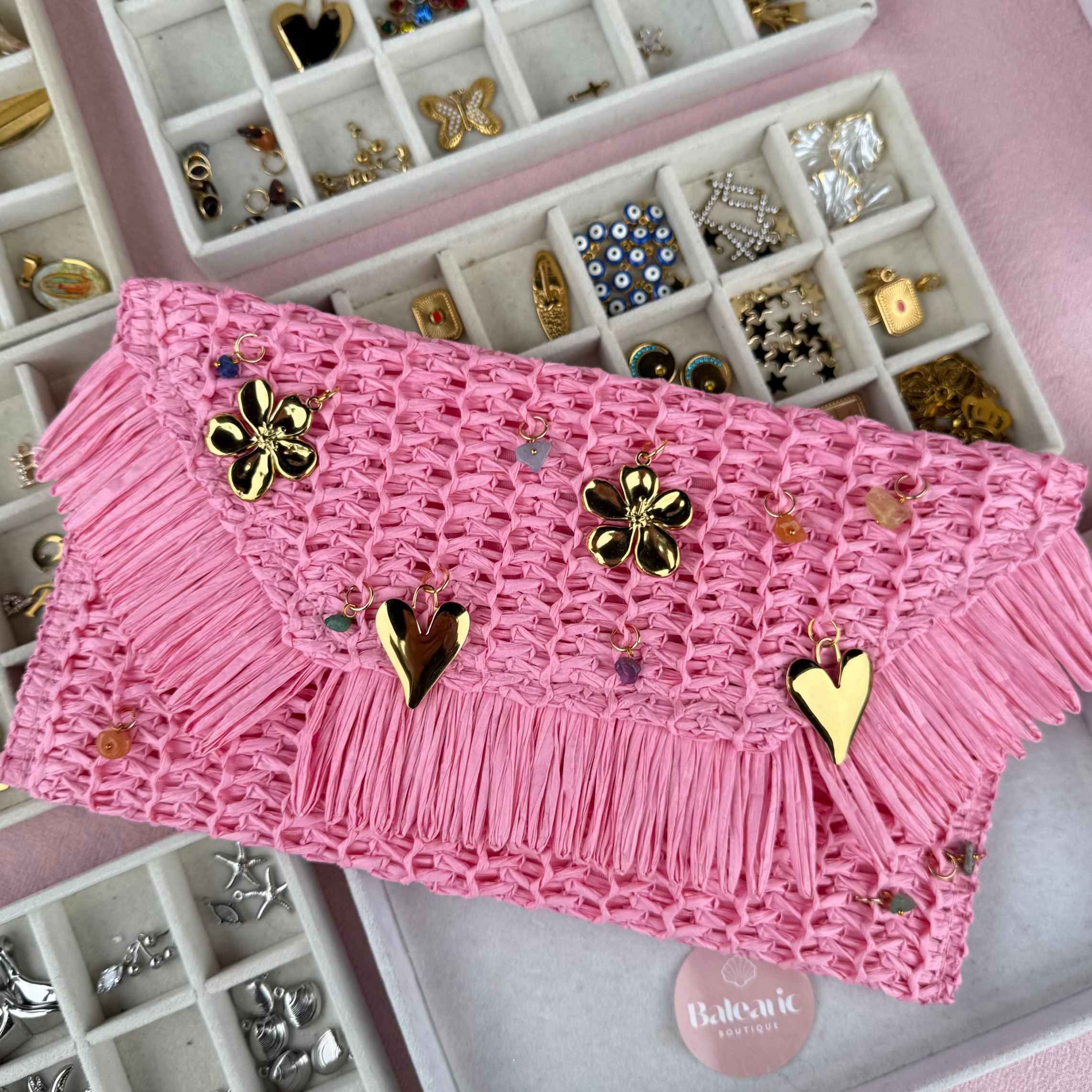 Pink clutch with gold embellishments on a pink jewelry box with jewelry compartments.