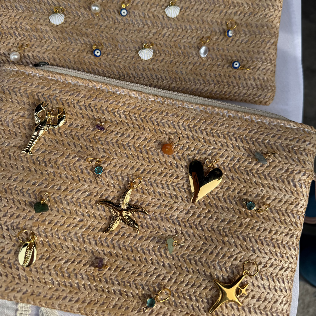 Beige clutch bag with decorative embellishments on a white surface