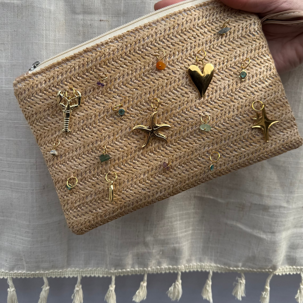 Handheld woven pouch with decorative charms on a light fabric background