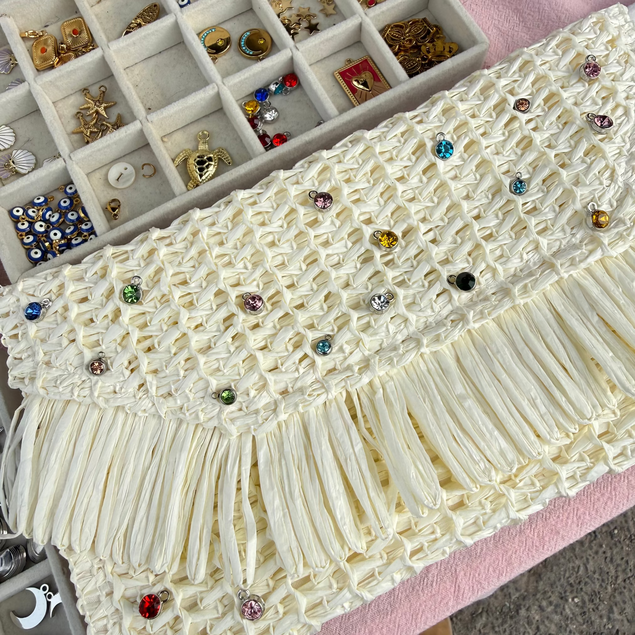 White lace fabric with embellishments on a pink surface next to jewelry boxes.